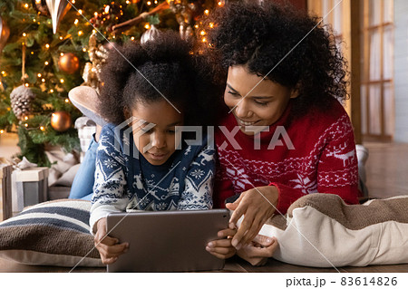 Happy biracial mom and daughter play on tablet at home Happy biracial mom and daughter play on tablet at home 83614826