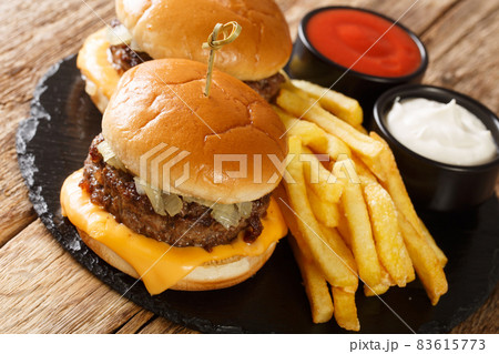 American butter burgers with beef, onions and cheese served with fries and sauces close-up. horizontal 83615773