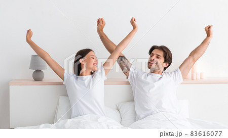 Happy attractive millennial european husband and wife stretching body and enjoying good morning 83616077
