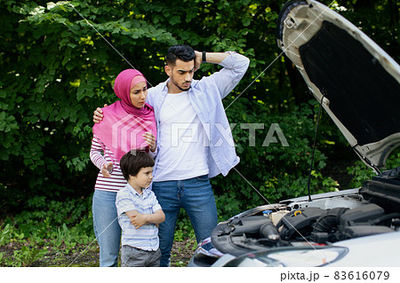 Confused Muslim Family With Little Son Standing Near Broken Car Outdoors 83616079