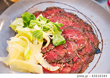 Carpaccio on a plate of vegetables and lemon. Italian cuisine.  83616384