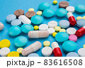 A lot of multi-colored pills on blue background, as a concept of medical treatment with a prescription. 83616508
