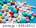 A lot of multi-colored pills on blue background, as a concept of medical treatment with a prescription. 83616511