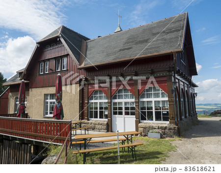 Old rustic building of Topferbaude viewpoint restaurant and hut next to hill Topfer near the town of Oybin at Zittauer Gebirge mountains nature park in Saxony, germany. Summer sunny day 83618621