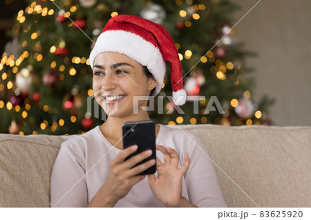 Dreamy happy young Indian woman typing greeting in cellphone. Dreamy happy young Indian woman typing greeting in cellphone. 83625920