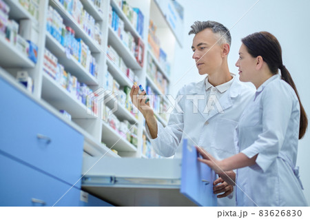 Man and woman interestedly considering medicine in pharmacy Man and woman interestedly considering medicine in pharmacy 83626830