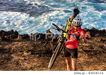 Mountain biking carrying bike uphill walking up hill. MTB biker cyclist riding outdoors. Cycling sports. 83628114