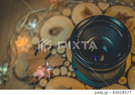 Soviet old lens with manual focus on a decorative wooden stand. Warm light. Top view, close up 83628577