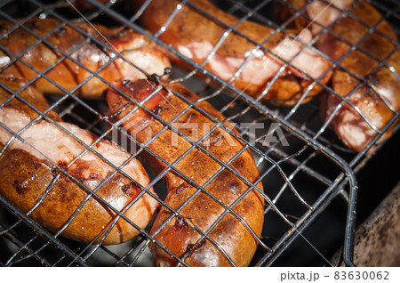 Close-up of hot sausages in the grill grill. The process of cooking. Close-up of hot sausages in the grill grill. The process of cooking. 83630062