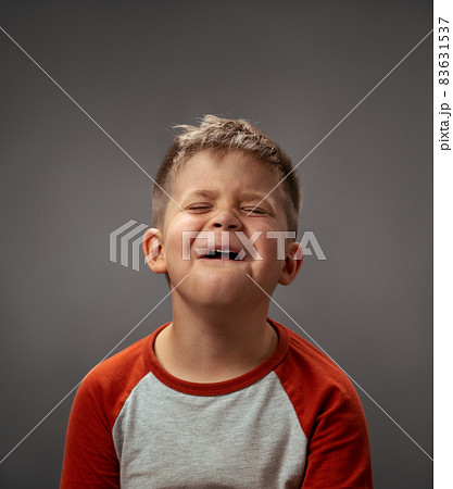 Portrait of a sad pretending cry little boy isolated on grey background. Fake emotions. Human emotions, facial expression concept. Facial expressions, emotions, feelings 83631537