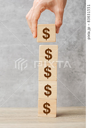 Businessman hand holding wooden blocks with the American Dollar symbol. Money, cash, currency and investment concept. Businessman hand holding wooden blocks with the American Dollar symbol. Money, cash, currency and investment concept. 83631551