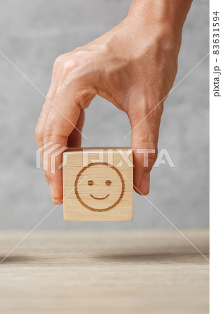 hand holding smile face block. Customer choose Emoticon for user reviews. Service rating, ranking, customer review, satisfaction, mood, mental health and feedback concept hand holding smile face block. Customer choose Emoticon for user reviews. Service rating, ranking, customer review, satisfaction, mood, mental health and feedback concept 83631594