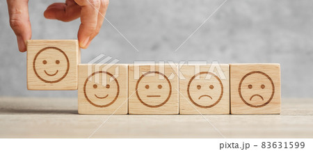 Man hand holding emotion face block. Customer choose Emoticon for user reviews. Service rating, ranking, customer review, satisfaction, mood, evaluation and feedback concept Man hand holding emotion face block. Customer choose Emoticon for user reviews. Service rating, ranking, customer review, satisfaction, mood, evaluation and feedback concept 83631599