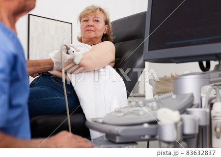 Woman during examination of hand with ultrasonography device 83632837