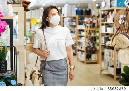 Latino woman in protective mask walking in household goods store 83632839