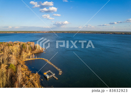 Colorful autumn forest with trees on the shore of a blue lake - top aerial view. Colorful autumn forest with trees on the shore of a blue lake - top aerial view. 83632923