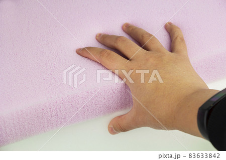 the hand presses on the surface of the rubber foam. Checking hardness and softness. Choosing the best type and quality. Close-up. the hand presses on the surface of the rubber foam. Checking hardness and softness. Choosing the best type and quality. Close-up. 83633842