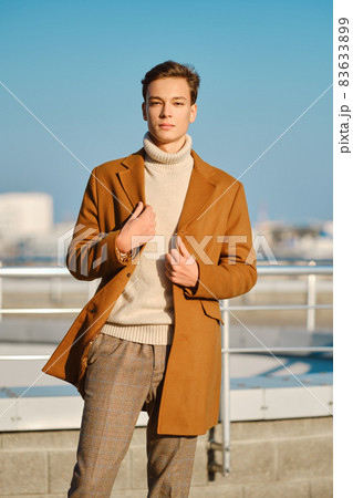 Young man in checkered trousers, sweater wraps wool coat outdoor Young man in checkered trousers, sweater wraps wool coat outdoor 83633899