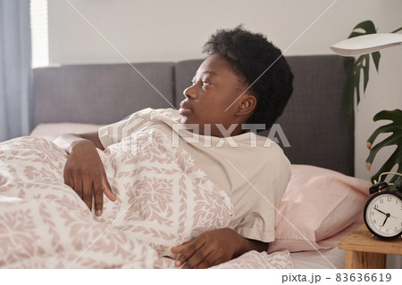 African young woman getting up early in the morning after sleeping in her bedroom 83636619