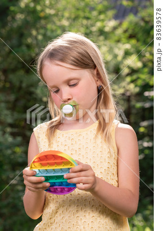 Child plays popit fidget toy outdoors Child plays popit fidget toy outdoors 83639578