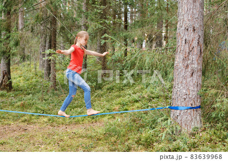 Girl balancing on slackline during summer holidays 83639968
