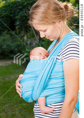 Mother carrying newborn baby in sling outdoors Mother carrying newborn baby in sling outdoors 83640118