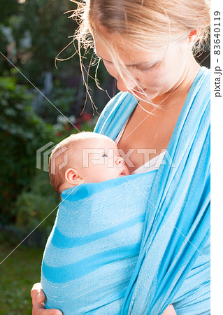 Woman with newborn baby in sling Woman with newborn baby in sling 83640119