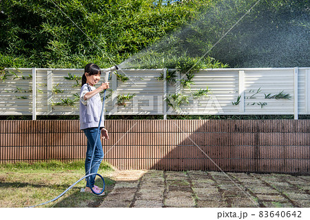 芝生に水やりをする小学生の女の子 83640642
