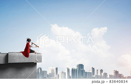 Girl power concept with cute kid guardian against cityscape background. Mixed media 83640834