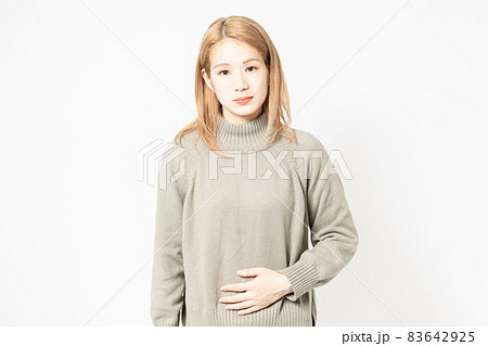 お腹を手で抑えるセーターを着た若い女性 お腹を手で抑えるセーターを着た若い女性 83642925