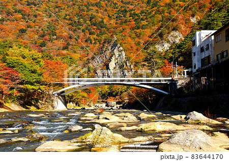 秋の紅葉に染まる塩原温泉と箒川と天狗岩 83644170