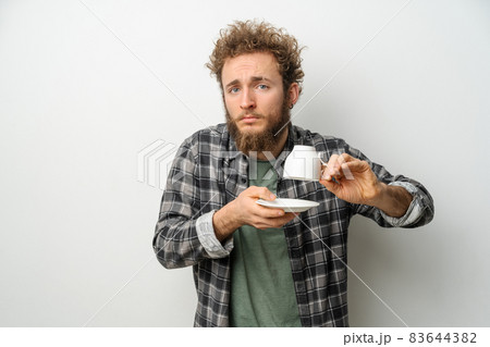 Good looking man with curly hair and beard holding inverted cup showing No coffee, guy wearing plaid long sleeve shirt isolated on white background. Crisis and lockdown concept Good looking man with curly hair and beard holding inverted cup showing No coffee, guy wearing plaid long sleeve shirt isolated on white background. Crisis and lockdown concept 83644382