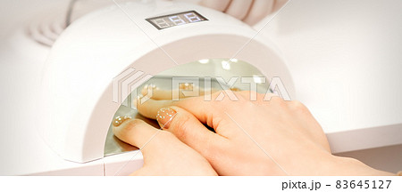 Female hand with manicured fingers dry inside UV light machine in manicure salon. Female hand with manicured fingers dry inside UV light machine in manicure salon. 83645127
