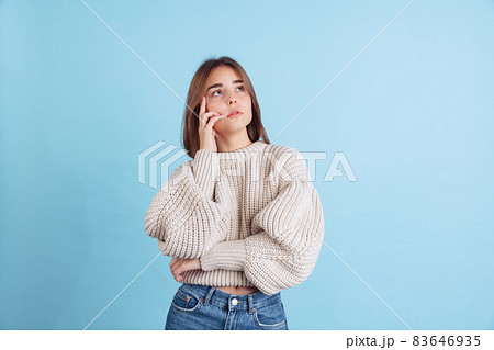 Portrait of young beuatiful girl, student in casual clothes looking up isolated on light blue studio backgroud 83646935
