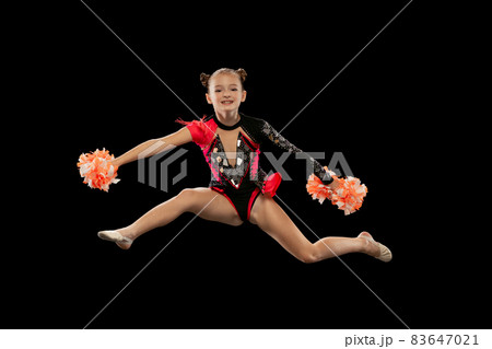 Full-length portrait of beautiful girl, cheerleader training, making movements in a jump isolated over black background Full-length portrait of beautiful girl, cheerleader training, making movements in a jump isolated over black background 83647021