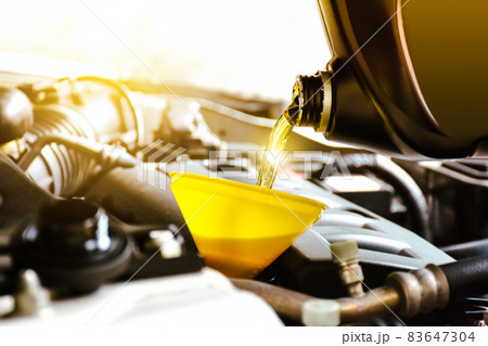Mechanic pouring motor oil to engine in the repair garage shop 83647304
