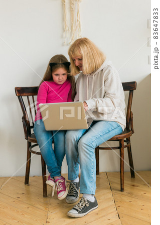 Child and granny using laptop in kitchen. Generation and family concept Child and granny using laptop in kitchen. Generation and family concept 83647833
