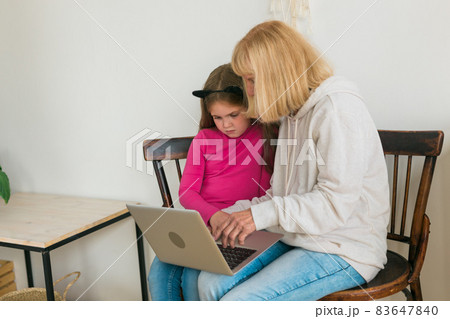 Child and granny using laptop in kitchen. Generation and family concept Child and granny using laptop in kitchen. Generation and family concept 83647840