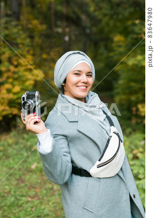 Young Arab Woman wearing hijab headscarf photographing with a smartphone in park. Modern muslim girl 83647980