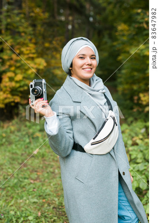 Young Arab Woman wearing hijab headscarf photographing with a smartphone in park. Modern muslim girl 83647982