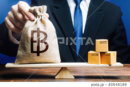 Thai baht money bag and a bunch of boxes on scales. Trade exchange balance. Manufacturing, retail distribution. Profit from manufactured goods. Import and export, economic processes. Thai baht money bag and a bunch of boxes on scales. Trade exchange balance. Manufacturing, retail distribution. Profit from manufactured goods. Import and export, economic processes. 83648189