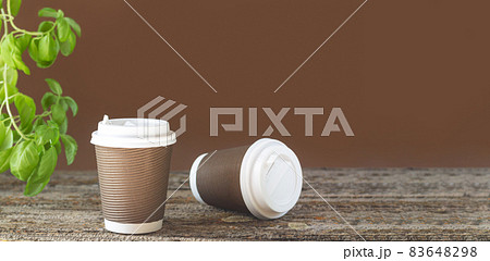Banner takeaway paper coffee cup on table with green plant Banner takeaway paper coffee cup on table with green plant 83648298