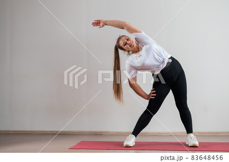 Young fat woman doing flexibility exercises on a white background Young fat woman doing flexibility exercises on a white background 83648456