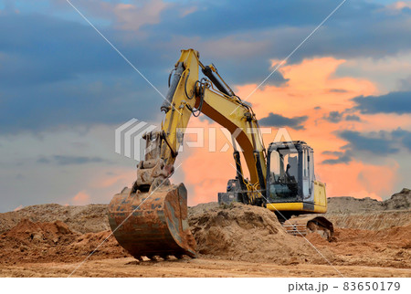 Excavator working on earthmoving at open pit mining on sunset background.  83650179