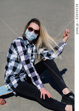 Portrait of a young female in a medical mask with longboard in the city during the quarantine 83650538