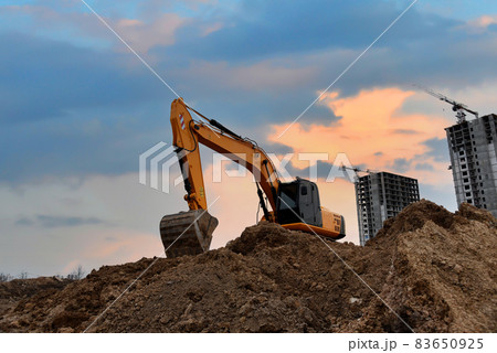 Excavator digging foundation at construction site.  83650925