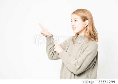 指でポイントを示すセーターを着た若い女性 83651299