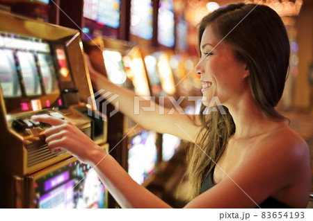 Asian woman gambling in casino playing on slot machines spending money. Gambler addict to spin machine. Asian girl player, nightlife lifestyle. Las Vegas, USA. 83654193