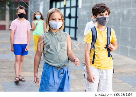 Portrait of little girl and boy wearing face mask walks along street 83656134