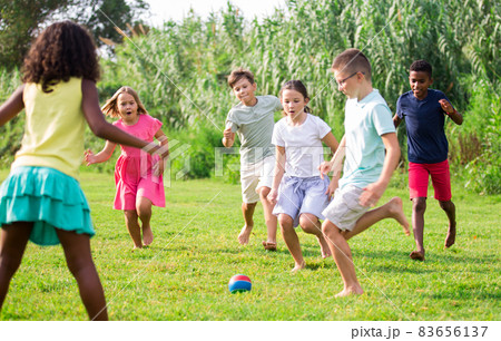 Kids running through grass and playing football Kids running through grass and playing football 83656137